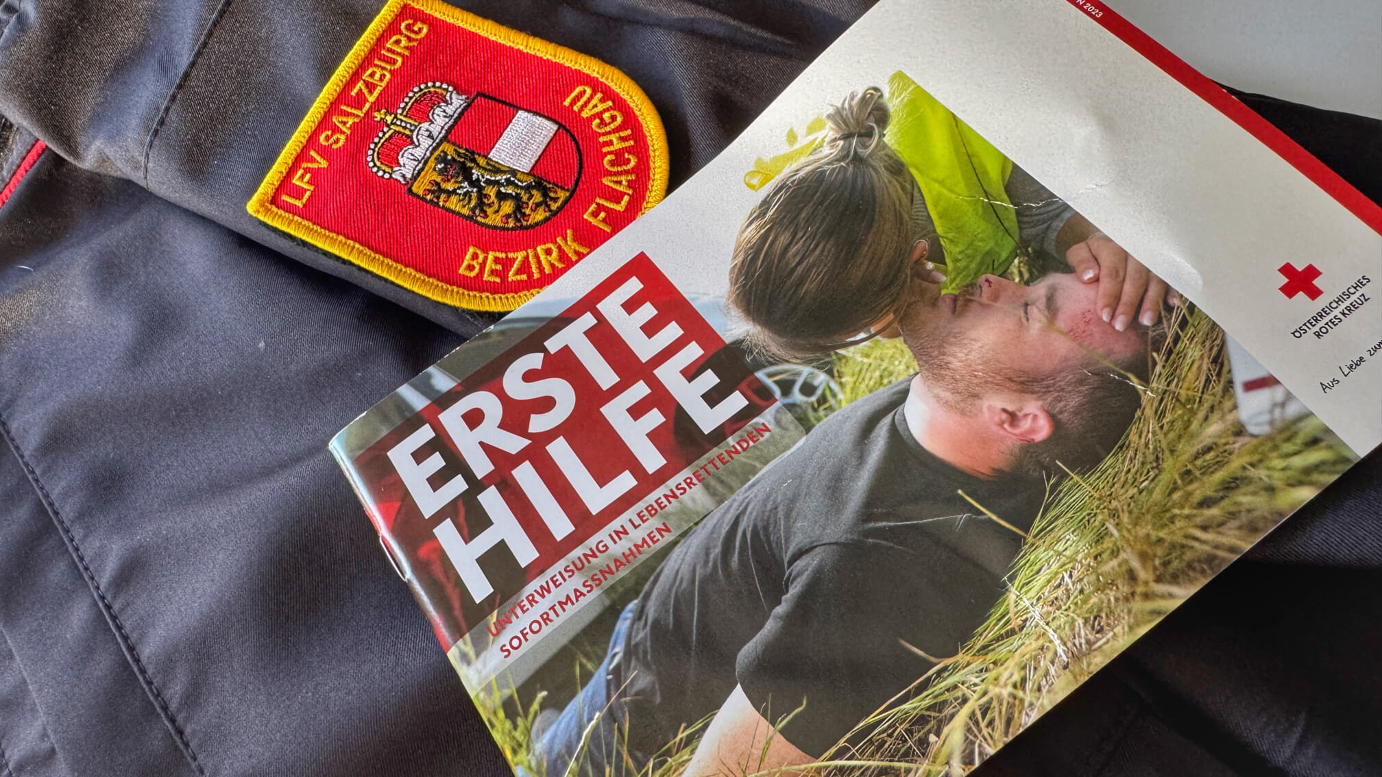 Erste-Hilfe-Handbuch auf Feuerwehruniform mit Logo des LFV Salzburg.
