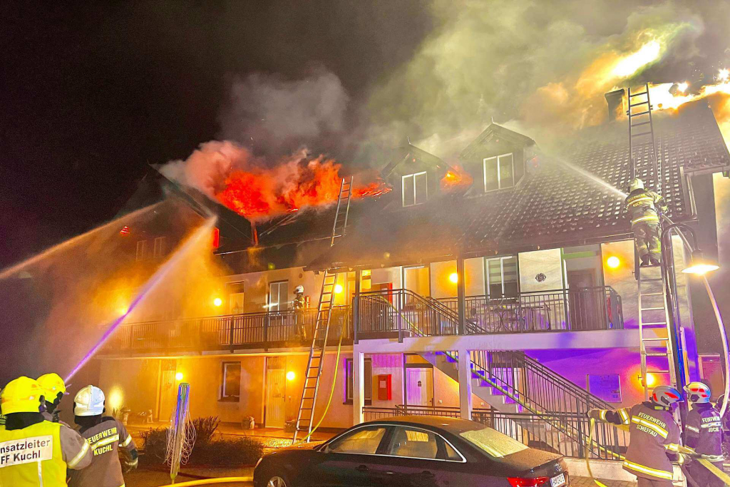Einsatzkräfte löschen Brand bei Wohnhaus, Flammen und Rauch sind sichtbar.